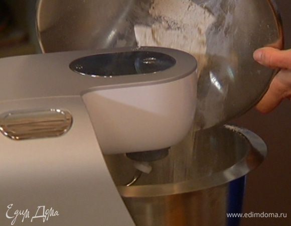 В чашу комбайна высыпать ржаную муку, залить ее 1/2 стакана воды и вымешать насадкой для теста. 