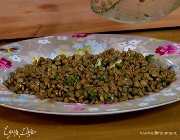В теплую чечевицу добавить 3/4 всей заправки, перемешать и выложить на большую тарелку.