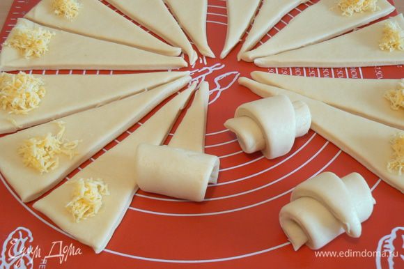 Стопку раскатать в круг диаметром 60-70 см. и разрезать его на треугольники. положить тертый сыр, свернуть рулетом.