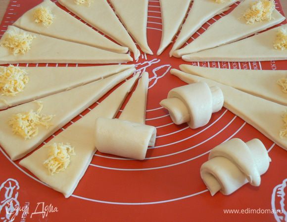 Стопку раскатать в круг диаметром 60-70 см. и разрезать его на треугольники.
 положить тертый сыр,  свернуть рулетом.