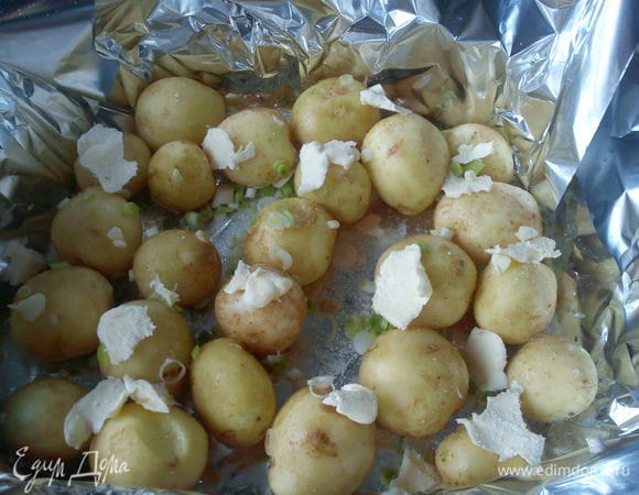 Картофель вымыть щеточкой. Форму для запекания застелить фольгой в несколько слоев. Выложить картофель, посыпать чесноком и солью, сверху разложить кусочками сливочное масло.