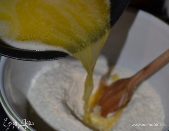 В глубокую миску просеять муку, сделать в ней углубление и залить горячую воду с маслом, тщательно размешивая деревянной ложкой. 