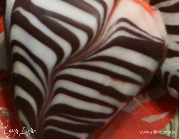Чтобы получить такой узор, нужно после нанесения белого шоколада , охладить. Затем нанести полоски молочного шоколада и шпажкой провести полосу сверху вниз, узор смешается, как на рисунке, и потом ставить охлаждать снова. 