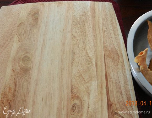  На коржи кладете нетяжелый груз (я использовала деревянную дощечку), чтобы они распрямлялись. Пока первый корж подрумянивается, раскатывайте следующий. Перед тем как класть следующий корж для раскатывания, дайте листу остыть. Хорошо иметь несколько листов для выпечки, дело пойдет намного быстрее. В итоге у вас получится 12 коржей под пресом и отдельно излишки.