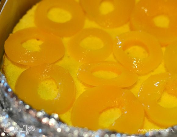 Форму снова застелить пергаментом, вырезать полоски, застелить также бока, форму хорошенько обернуть фольгой. Положить на дно формы бисквит, на бисквит выложить фрукты.