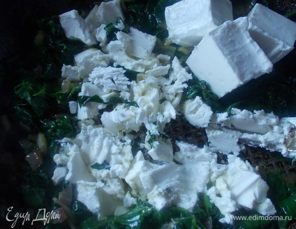 Лук мелко порезать и обжарить на масле до прозрачности. Затем добавить шпинат и протушить пару минут. После выключить огонь и добавить порезанную мелко зелень и фету. Размять фету вилкой и добавить в начинку.