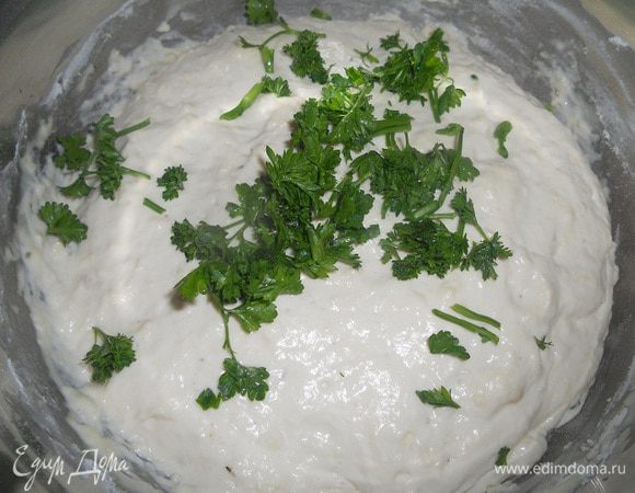 Когда подойдет тесто, нарвать петрушку, перемешать и добавить остальную муку, переложить в форму .