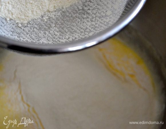 Ввести в яйца просеянную муку с разрыхлителем, перемешать деревянной ложкой движениями снизу вверх до получения однородной массы.   