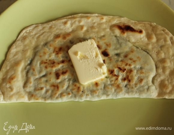 Готовые кутабы обильно смазать сливочным маслом и уложить стопкой.