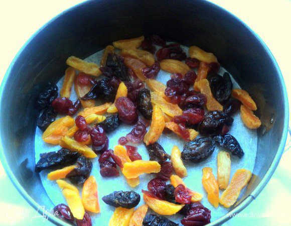 Дно формы Ф-20см застелить бумагой для выпечки, смазать растительным маслом и  выложить равномерно сухофрукты.