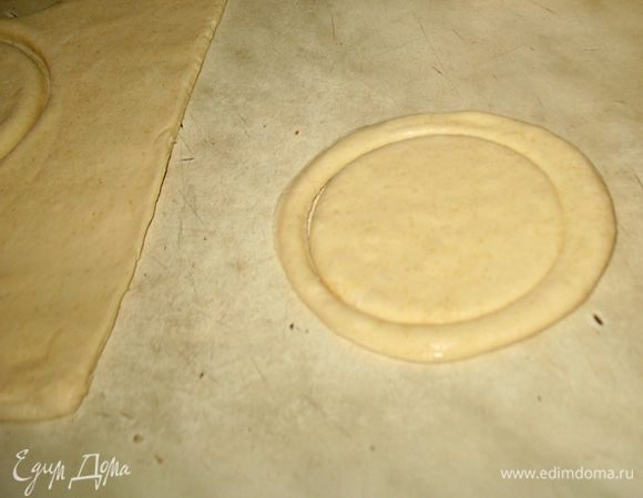 Раскатываем тесто толщиной 0,5 см. Из теста вырезаем 8-мь кругов диаметром 10 см,  в 4-х из них вырезаем меньшего диаметра круги, не вынимаем, оставляем на месте.  
Целые круги по краю смазываем водой и сверху выкладываем круги с вырезанными кругами. Слойки смазываем взбитым желтком. Слойки выкладываем на застеленный пергаментом противень и ставим в предварительно разогретую до 190 градусов духовку минут на 10. Дальше снижаем температуру до 170 градусов и выпекаем слойки еще минут 15 до золотистой корочки. Вынимаем слойки даем немного остыть и вынимаем вырезанные круги, т.е. крышечки. 
