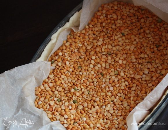 Чтобы тесто не деформировалось и не вздувалось,насыпаем горох или фасоль,на предварительно постеленный пергамент.Ставим в духовку на 10 минут.