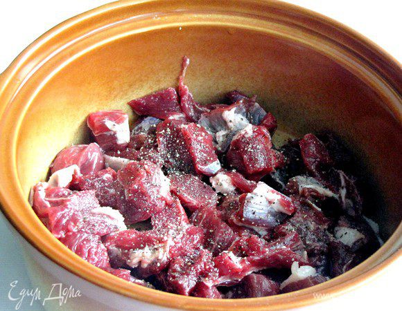 Мясо нарезать небольшими кубиками, уложить на дно горшка или керамической формы с крышкой, посолить, поперчить.