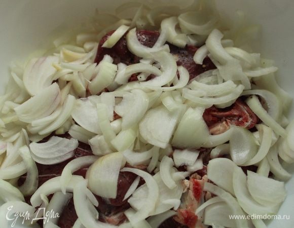 Положить мясо в чашку, сверху выложить лук, порезанный полукольцами.
