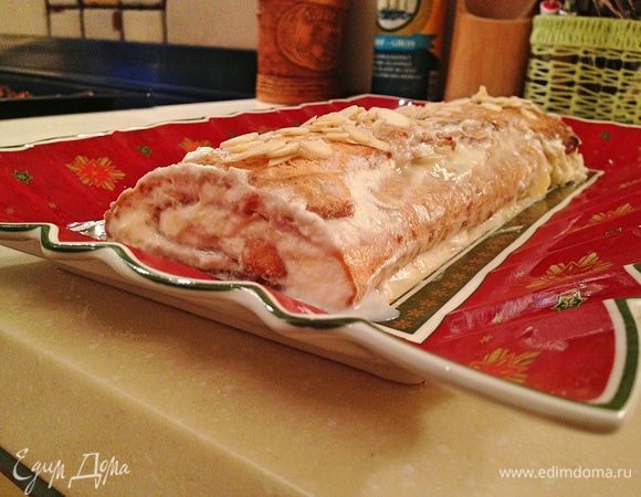 Переложить рулет, с помощью бумаги, на блюдо. Посыпать сахарной пудрой и оставшимися лепестками миндаля. Убрать  в холодильник на 1 час. Нарезать порционными кусочками. Приятного аппетита! 