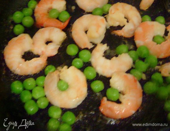 На другой сковородке обжарить на оливковом масле в течение 3 мин. креветки и горошек.