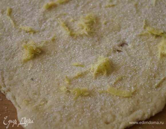 На подпыленном мукой, столе раскатать в тонкий пласт тесто. В отдельной миске смешать натертую апельсиновую цедру, имбирь и сахар. Выложить смесь на пласт теста.