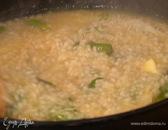 Готовое ризотто снять с огня, добавить оставшееся сливочное масло, большую часть натертого сыра и все вымешать.