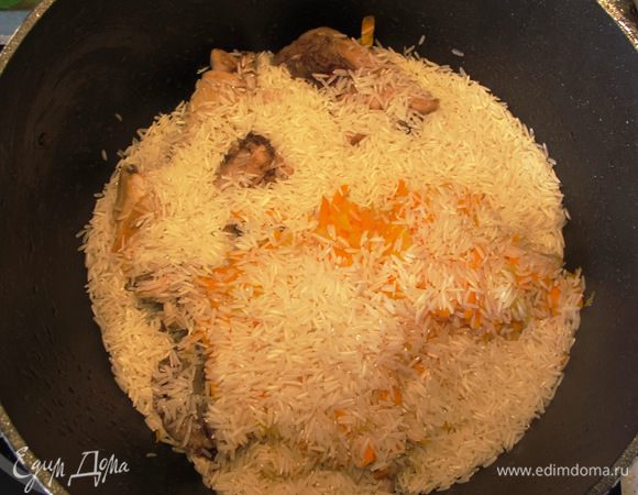 Рис промойте. Добавьте лук, чеснок и морковь к курице, всыпьте рис.