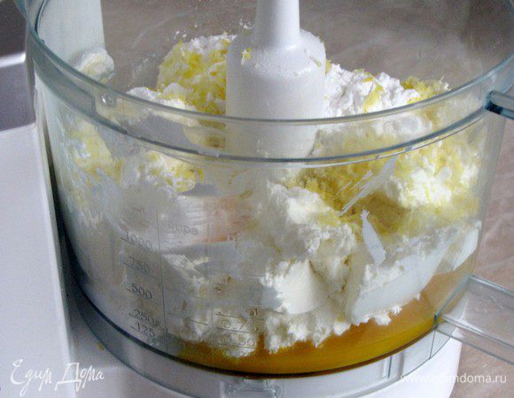 Пока тесто застывает приготовим начинку. В чашке миксера смешайте сливочный сыр, яичные желтки, сахарную пудру, цедру лимона, ванильный сахар и крахмал. 