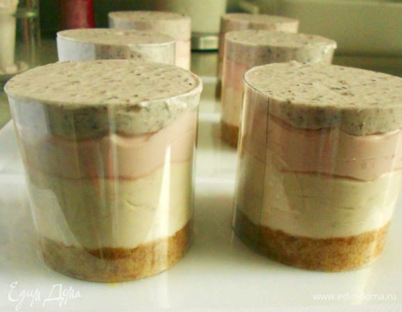 Теперь в подготовленные кольца с основой   выложить крем слоями. Начинать надо с клубничного, затем малиновый и завершить черничным.
Удобнее, конечно, это делать из кондитерских мешков с широкими насадками, но можно выкладывать и просто ложкой, только очень аккуратно, чтобы не смешивать слои.
Кольца должны быть заполнены до верхнего края. Выровнять верх ножом или шпателем.
Убрать десерт в холодильник минимум на 4 часа или на ночь. Он может храниться в холодильнике до 3-х дней.