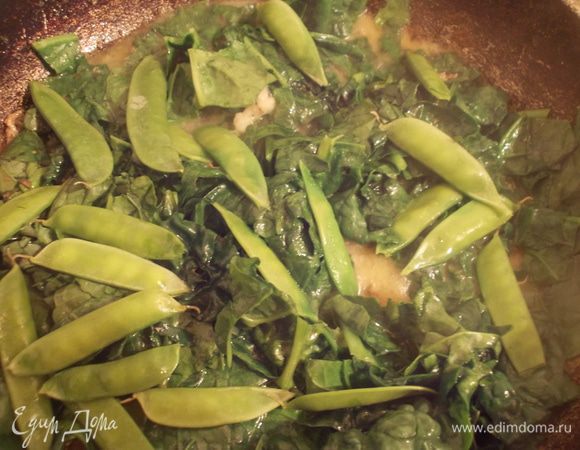 Затем выложить готовую курицу на отдельную тарелку. В сковороду, с оставшимся маслом и соками после тушения,добавляем измельченный чеснок и горох в стручках. Протушиваем пару минут,затем добавляем шпинат и ещё готовим минуту. 