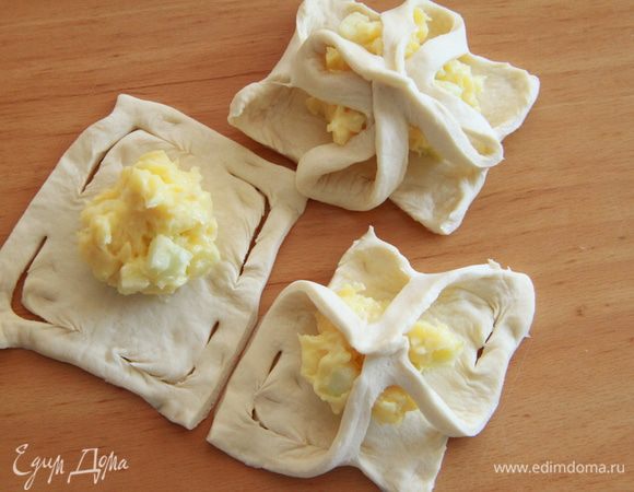 На середину квадратов выкладываем крем. Противоположные уголки соединяем посередине.