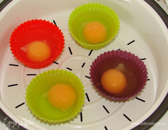 Формочки для кексов смазать растительным маслом, в каждую вылить по сырому яйцу.