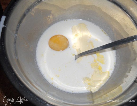 В другую миску к сливкам, перемешанным с водой, добавить сахар, яйцо, 70 г размягченного сливочного масла и хорошо перемешать.