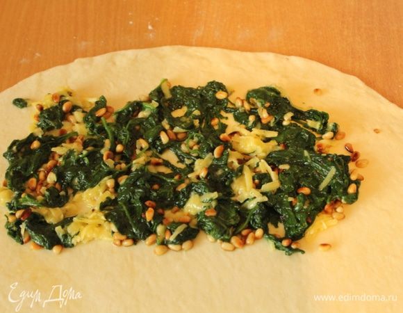 На присыпанной мукой рабочей поверхности раскатать тесто в тонкий круглый пласт. Условно разделить его на 2 равные части. На одну половинку выложить начинку.