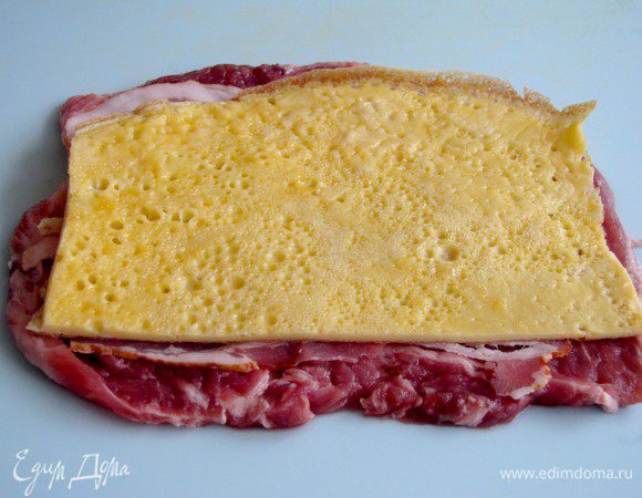 Сверху на бекон положите кусочек яичного блинчика.