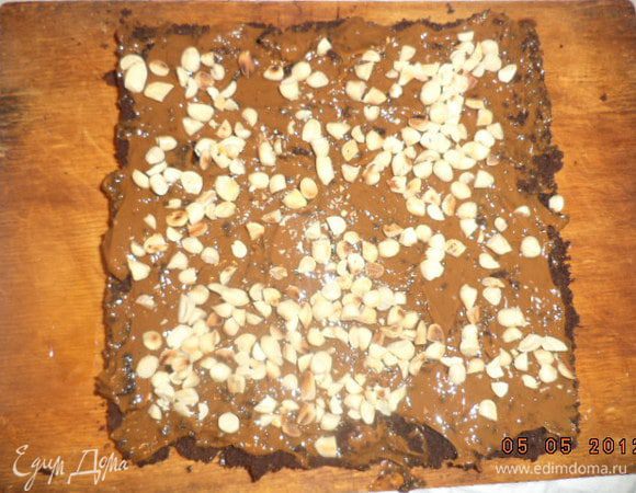 Нижний корж смазать сгущёнкой, посыпать половиной орехов. Накрыть вторым коржом.