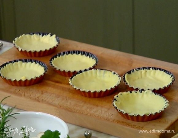 Из теста вырезать небольшие круги по размеру формочек для выпечки (можно вырезать самими формами) и равномерно распределить тесто по дну и бортикам.