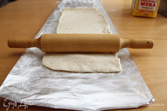 Займёмся тестом. Предварительно размороженное тесто выложить на пекарскую бумагу (у меня на тот момент её не было, поэтому на фото фольга), начать раскатывать. Должна получиться "дорожка" длиной 60-70 см и шириной 30-40 см.