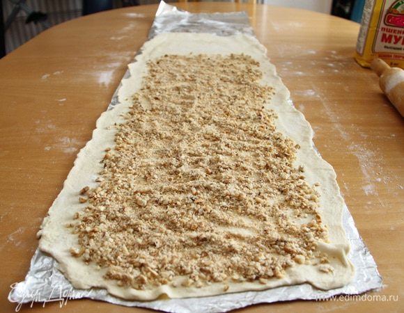 Выложить на тесто орехово-печенюшные крошки таким образом, чтобы по краям слева и справа оставалось чистое тесто 3-5 см, а на дальнем от вас крае - 10-15 см.
