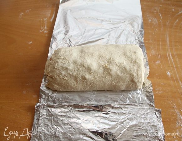 Теперь слева и справа загибаем края теста к центру на 3-5 см. Заворачиваем рулет, оставляя бумагу на столе.