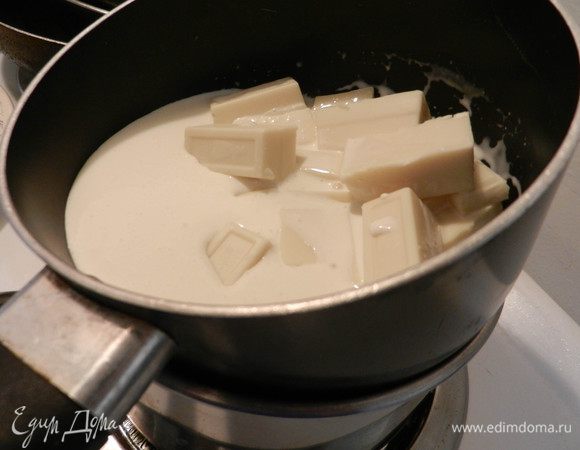 Плитку белого шоколада ломаем на кусочки, заливаем сливками и нагреваем, помешивая, даем шоколаду растопиться и дойти смеси до кипения. Снять с огня. (Можно это делать в микрокволновке).