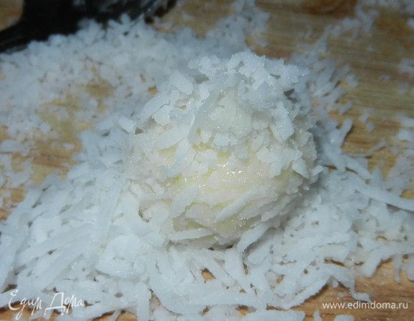 Можно приступить лепить конфетки. 
На любую поверхность насыпаем кокосовую стружку. 
Одной чайной ложкой набираем крем, второй - скидываем в кокосовую стружку. Кладем орех, чуть притапливаем и формируем конфетку. Старайтесь всё делать при помощи ложек, так как от прикосновения рук крем размягчается, почти тает. Получившиеся конфеты обваливаем в стружке. Когда вы обваляли в стружке, теперь можно при помощи ладошек придать форму (кокосовая стружка предохраняет конфеты от растапливания в ваших теплых руках).
(Если смесь сильно размягчится в процессе лепки, поставить снова в холодильник на некоторое время).