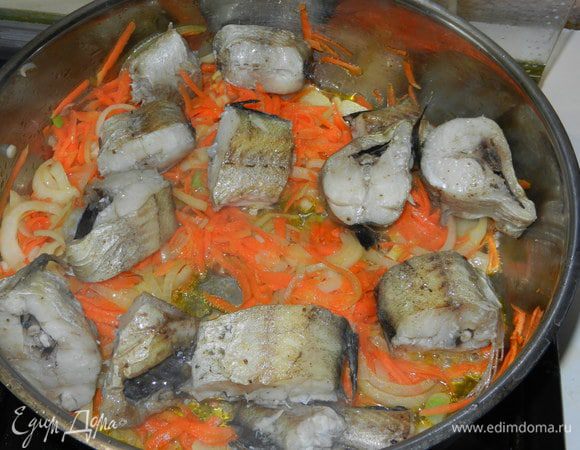 В сотейнике пассеруем тонко нарезанный лук полукольцами и натертую на крупной терке морковь до полуготовности. Добавляем соль и смесь перцев. Выкладываем на "подушечку" нашу рыбу и на медленном огне тушем несколько минут под крышкой.