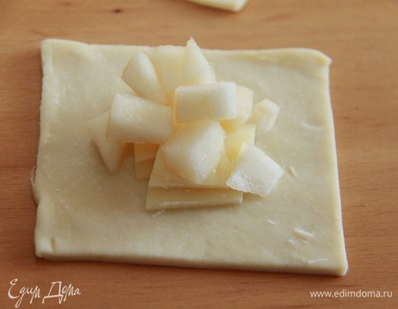 Края квадрата смазываем белком (или яйцом). В центр квадрата кладём сыр и грушу. Соединяем края по диагонали и прижимаем.