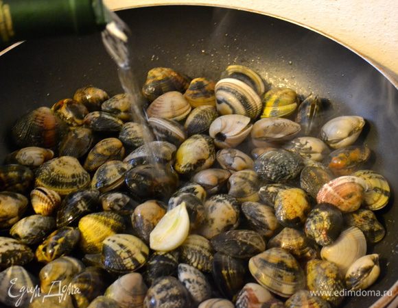 Выложить на сковороду моллюсков. Потряхивая сковороду, дать им обжариться в подготовленном масле. Буквально 1 минуту. Затем добавить стакан белого вина и накрыть сковороду крышкой.   