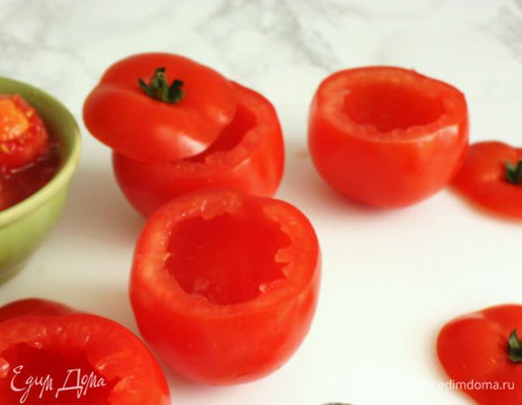 Помидоры лучше выбирать с плодоножкой. Ножницами укоротить листочки на ней. Помидоры помыть и у каждого срезать верхнюю часть с плодоножкой в виде крышечки. Ложкой выбрать мякоть, отложить в миску.