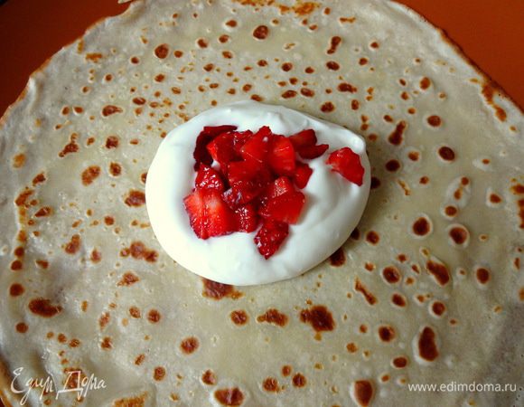 Приступаем с сборке мешочков. На блинчик кладем по столовой ложке взбитых сливок и порезанной клубники.