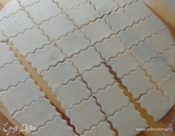 Раскатать тонко, часто наколоть вилкой и разрезать на небольшие квадратики.