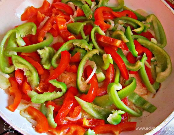 К луку добавить нарезанный соломкой перец, дольки помидор и потушить 7 мин.
