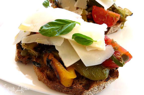 Уложить на хлеб овощи, присыпать пармезаном и накапать сверху пару капель оливкового масла.