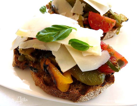 Уложить на хлеб овощи, присыпать пармезаном и накапать сверху пару капель оливкового масла.
