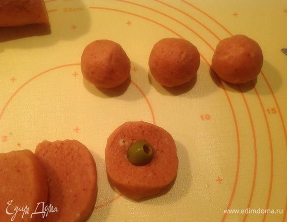 Дать оливкам стечь. В каждый кусочек теста вложить оливку и сформировать  шарик.