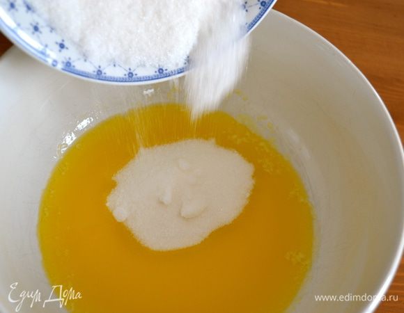 Тем временем приготовить крем. Для этого растопить сливочное масло на водяной бане (или в микроволновой печи). Перелить растопленное масло в миску, добавить к нему сахар и перемешать венчиком или деревянной ложкой. 