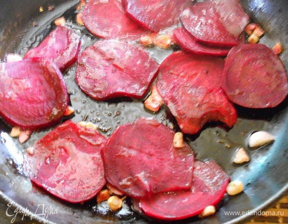 Тем временем почистить свеклу и нарезать тонкими кружочками. Добавить ее к чесноку на сковороду.